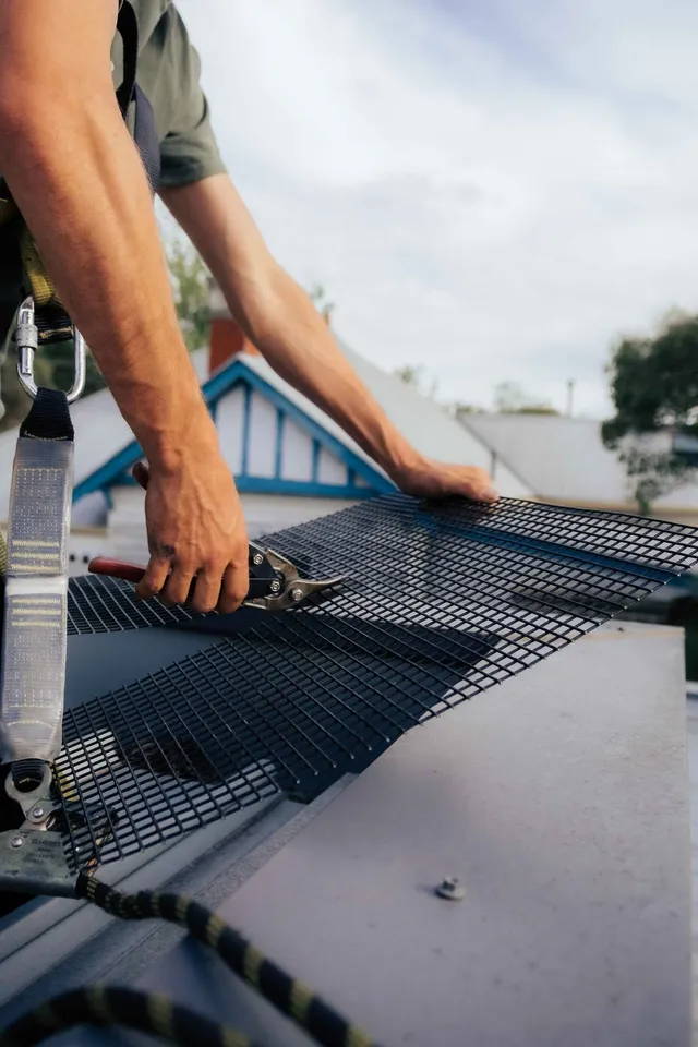Cutting steel mesh to possum-proof a roof